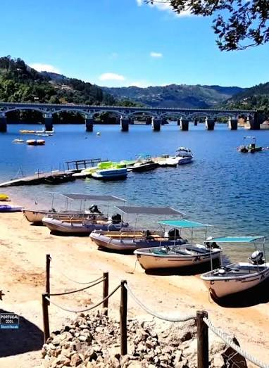 Praia fluvial do Cávado com barcos e ponte sobre a albufeira