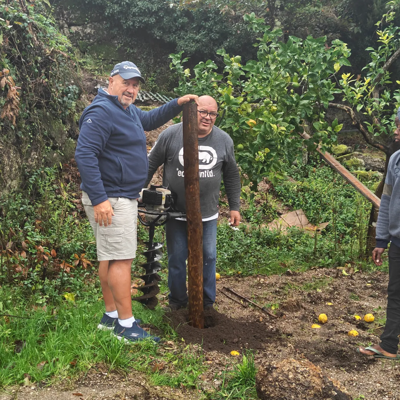 A família a colocar os postes de madeira