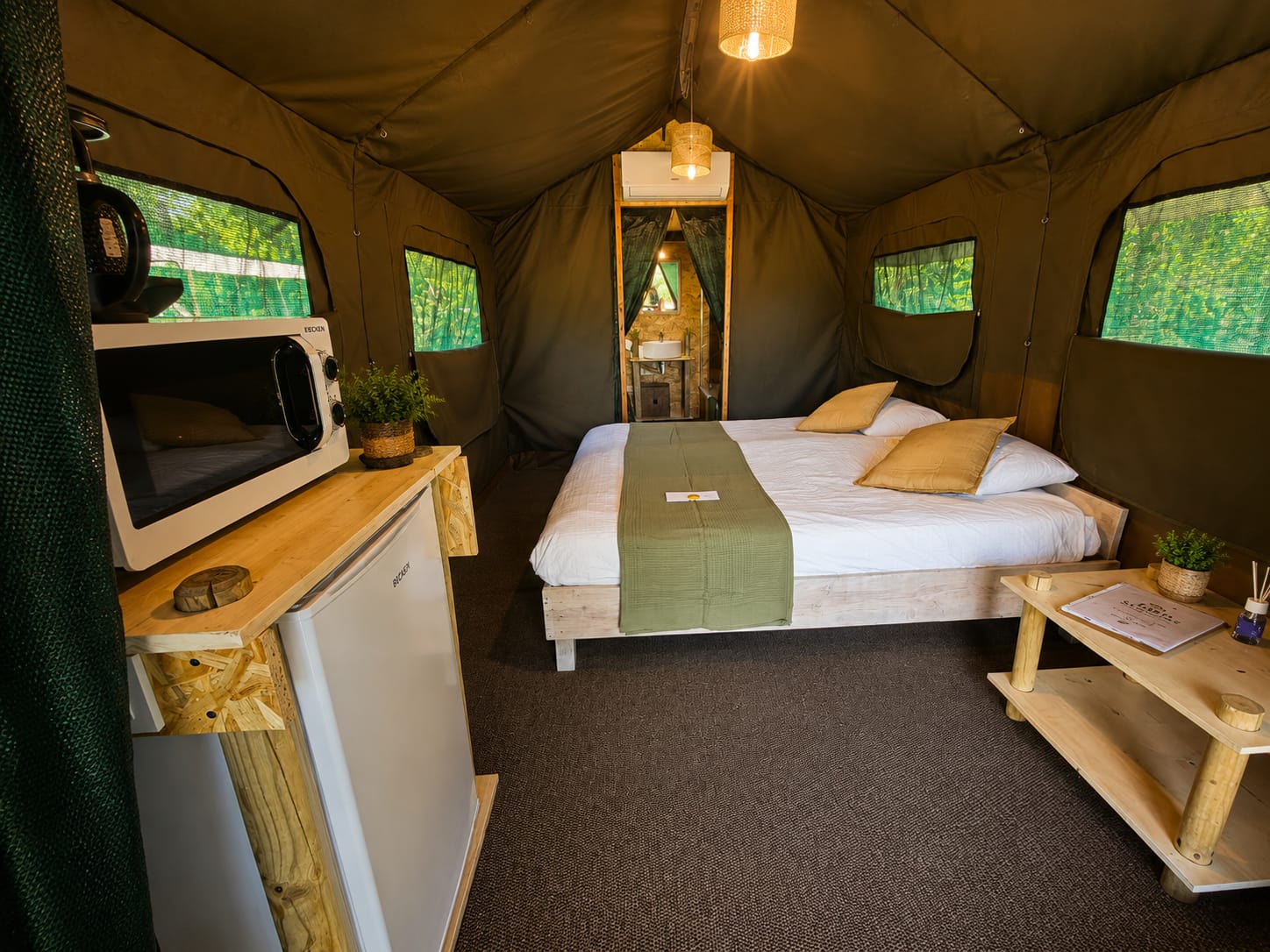 Interior de uma tenda safari com cama de casal e casa de banho privativa
